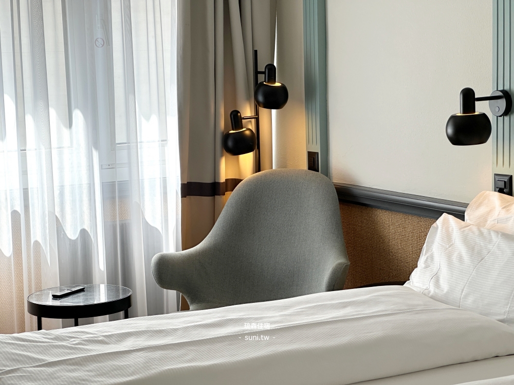 Hotel Luzernerhof房間床鋪白色枕頭灰色扶椅黑色壁燈